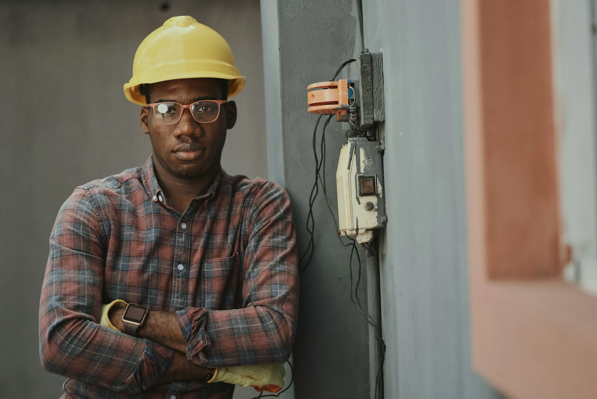 Electrician with folded arms standing beside a home electrical meter
