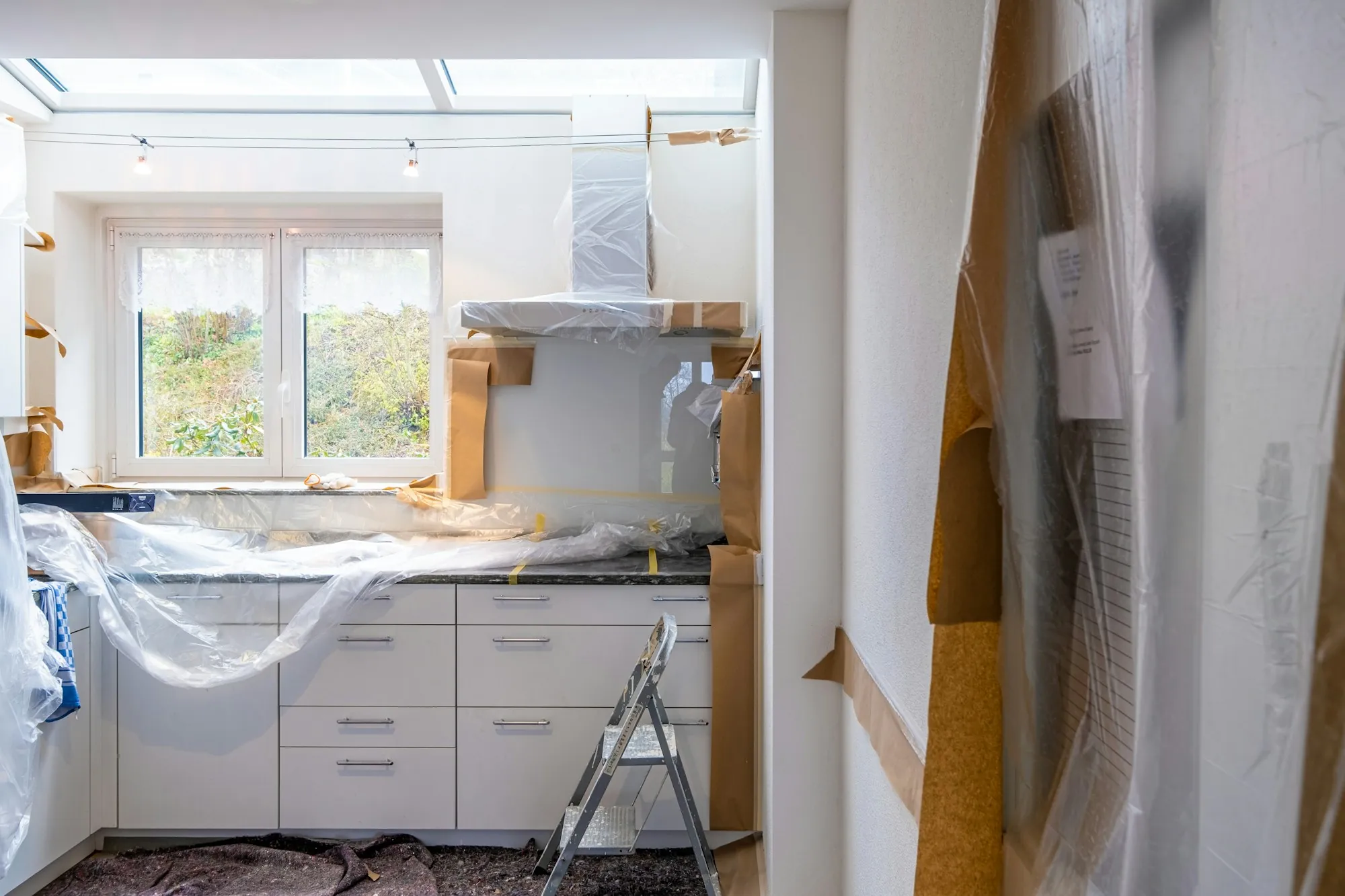 Kitchen mid-renovation with cabinets installed and protective sheeting