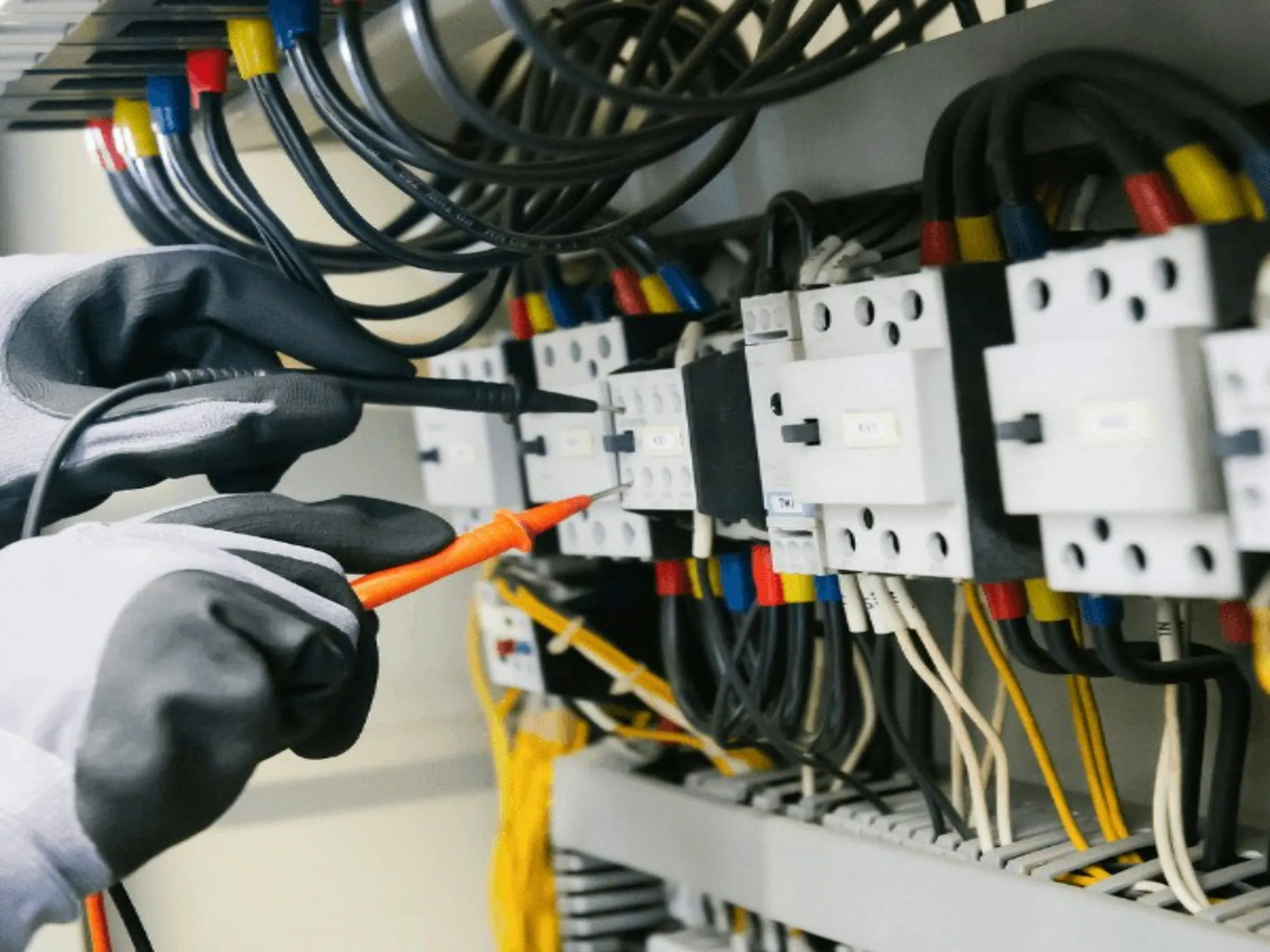 Gloved hand testing breakers inside an electrical panel