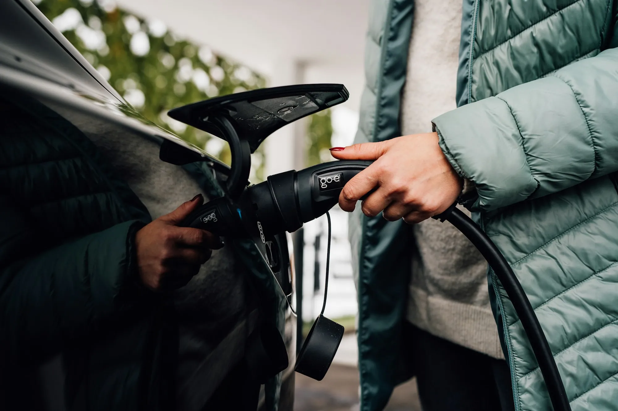 Person plugging a charging connector into an electric car