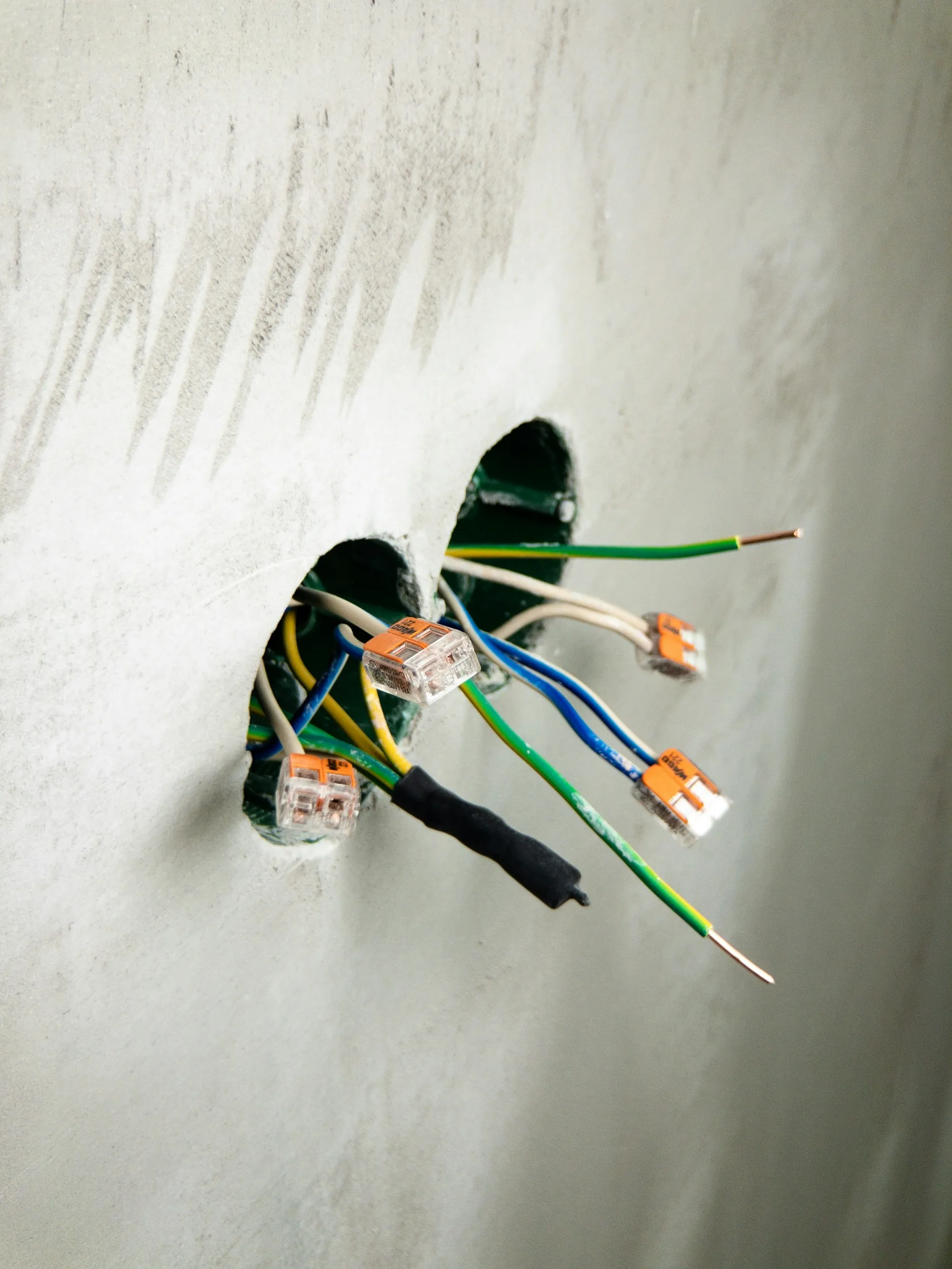 Bundle of wires emerging from an opening in a white wall