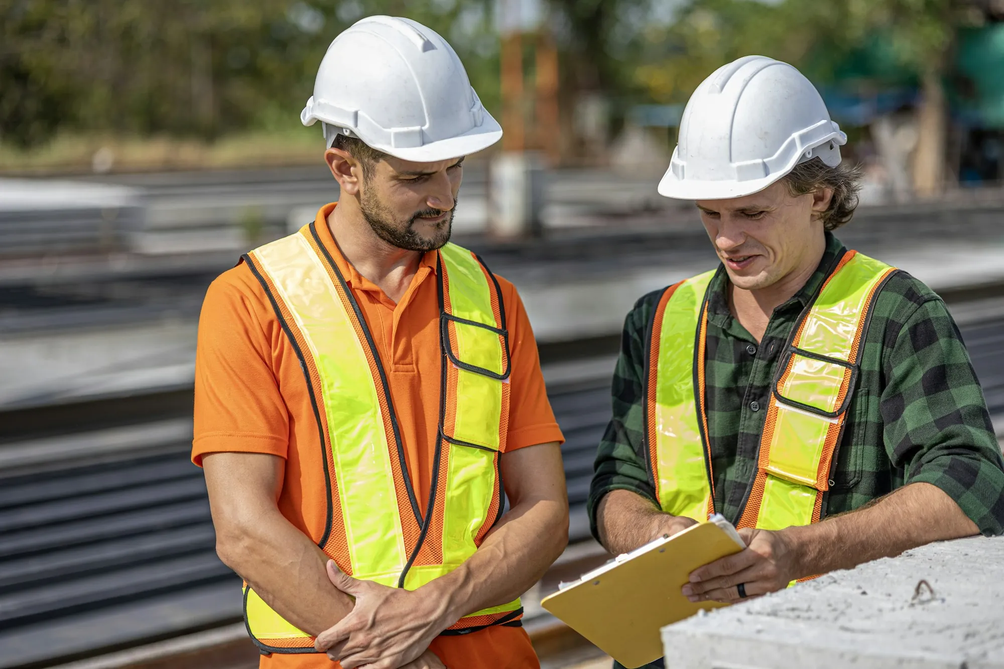 Two electricians in safety vests talking through a job outdoors